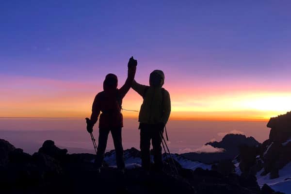 Trekkers celebrate reaching the summit after climbing Kilimanjaro
